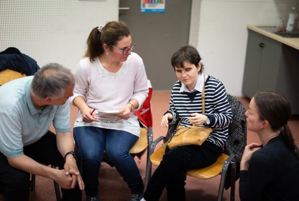 Kiscsoportos megbeszélés egy közösségi workshopon: a körben ülő résztvevők elmélyülten, egymásra figyelve dolgoznak együtt egy feladaton. Az aktív jelenlét és a közvetlen párbeszéd nyitott, befogadó légkört teremt az ötleteléshez és a tapasztalatcseréhez.