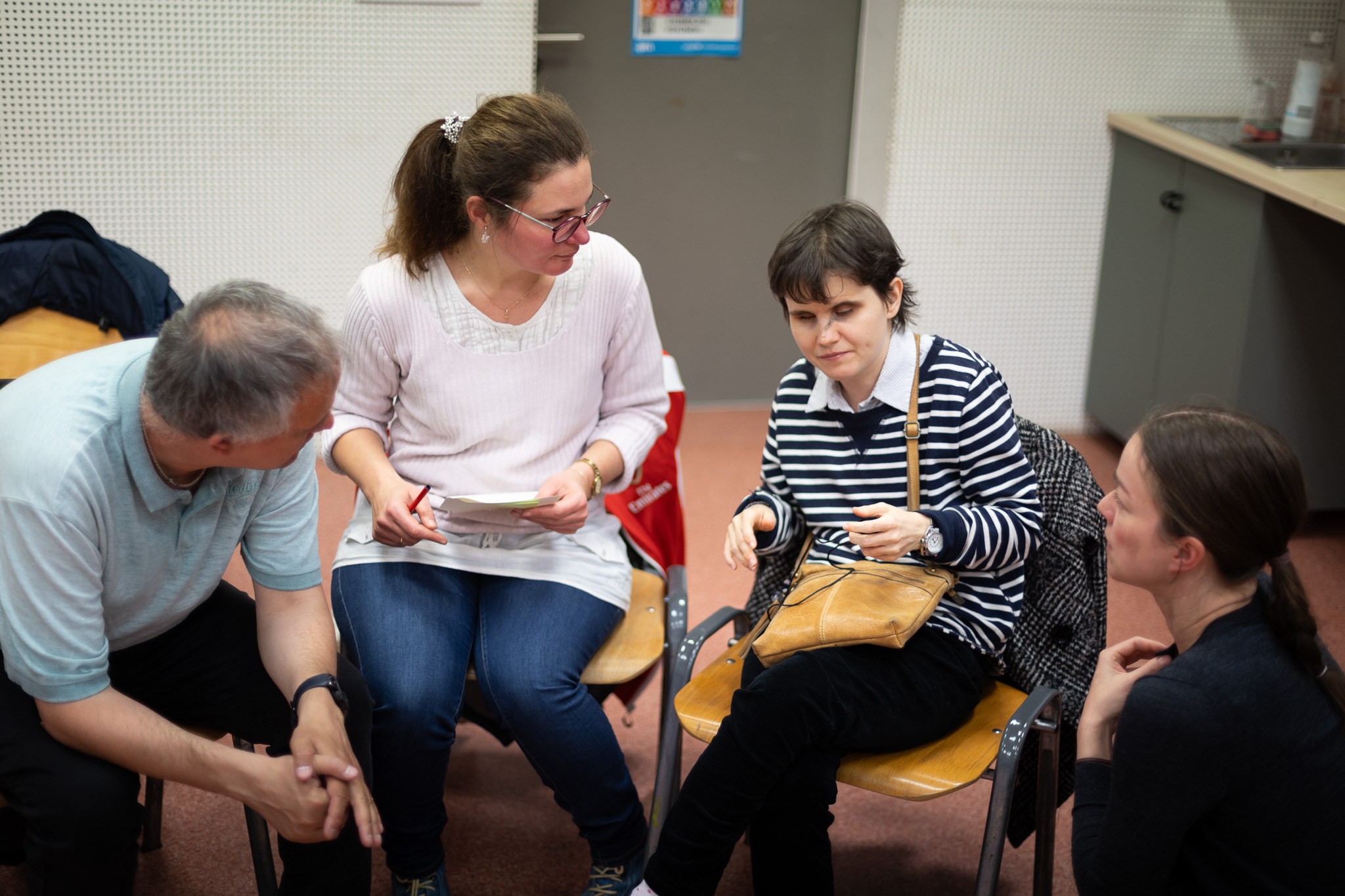 Kiscsoportos megbeszélés egy közösségi workshopon: a körben ülő résztvevők elmélyülten, egymásra figyelve dolgoznak együtt egy feladaton. Az aktív jelenlét és a közvetlen párbeszéd nyitott, befogadó légkört teremt az ötleteléshez és a tapasztalatcseréhez.